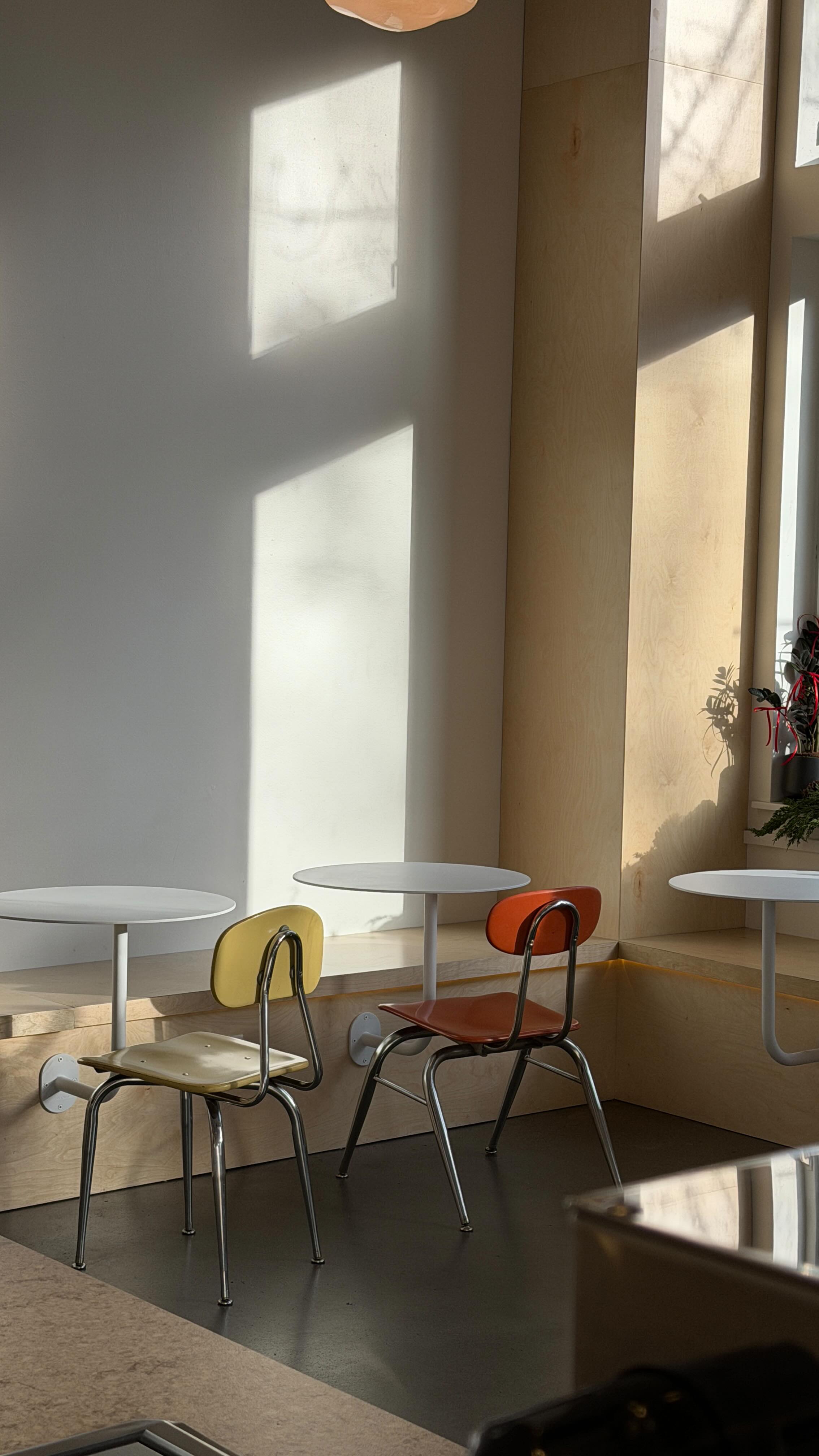 Late afternoon sun across a row of mismatched chairs and small round tables in the Yoka Tea cafe